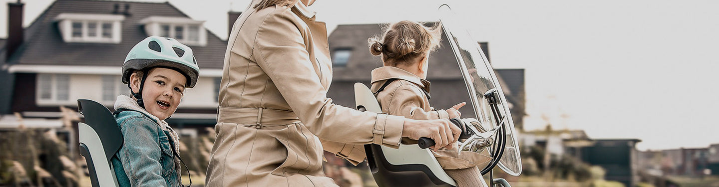 Femme à vélo avec des sièges enfants et un pare brise à l'avant