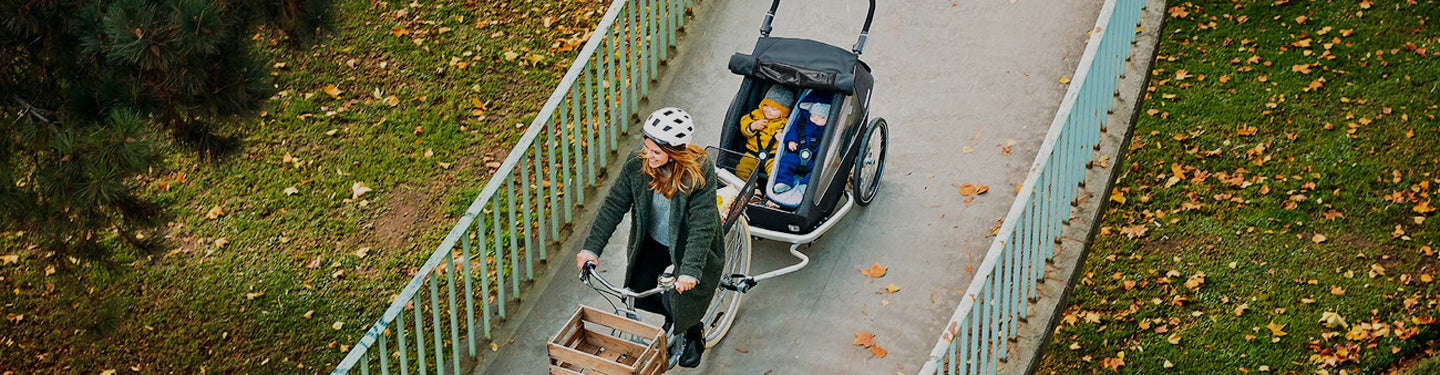 Femme à vélo avec des bébés dans une remorque