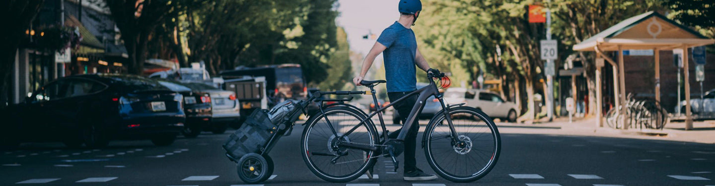 Cycliste en ville avec un chariot de course derrière son vélo