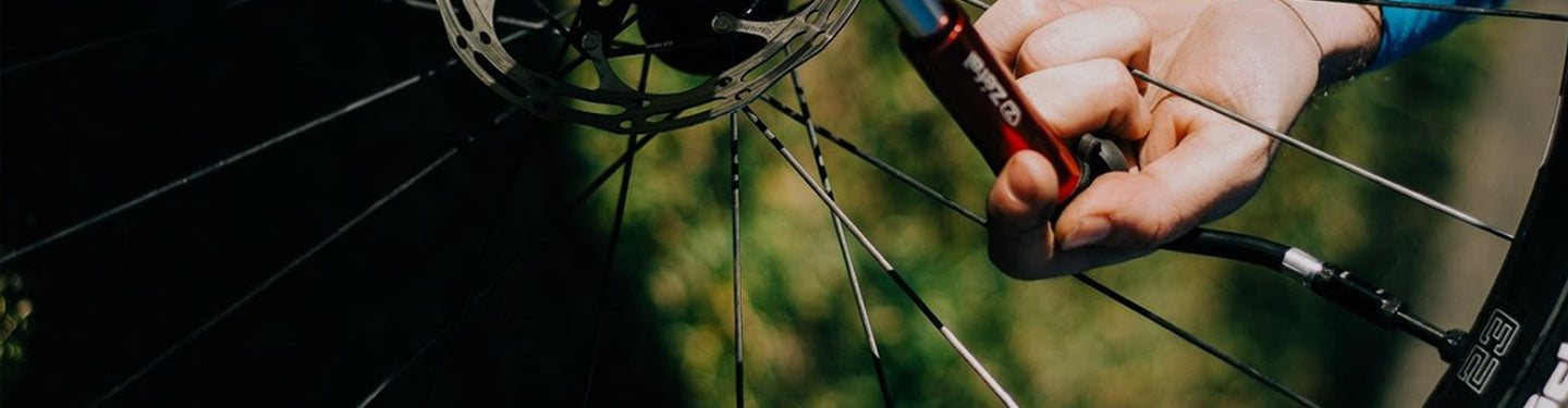 Personne qui gonfle son pneu vélo à l'aide d'une pompe à main Zefal