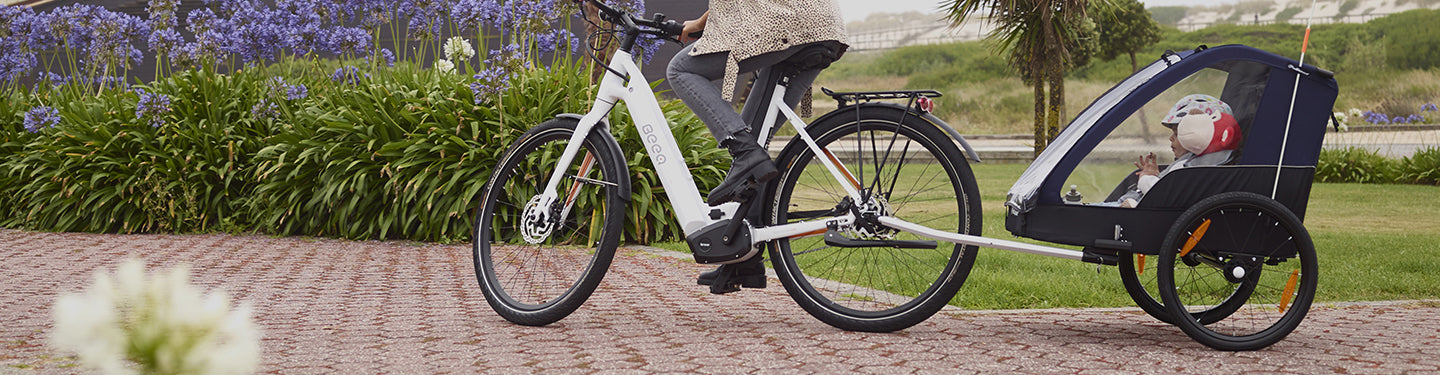 Personne qui fait du vélo avec une remorque enfant 