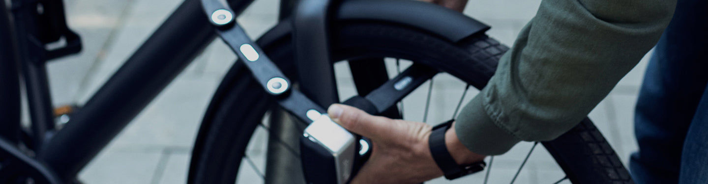 Personne accrochant son vélo avec un antivol connecté pliable