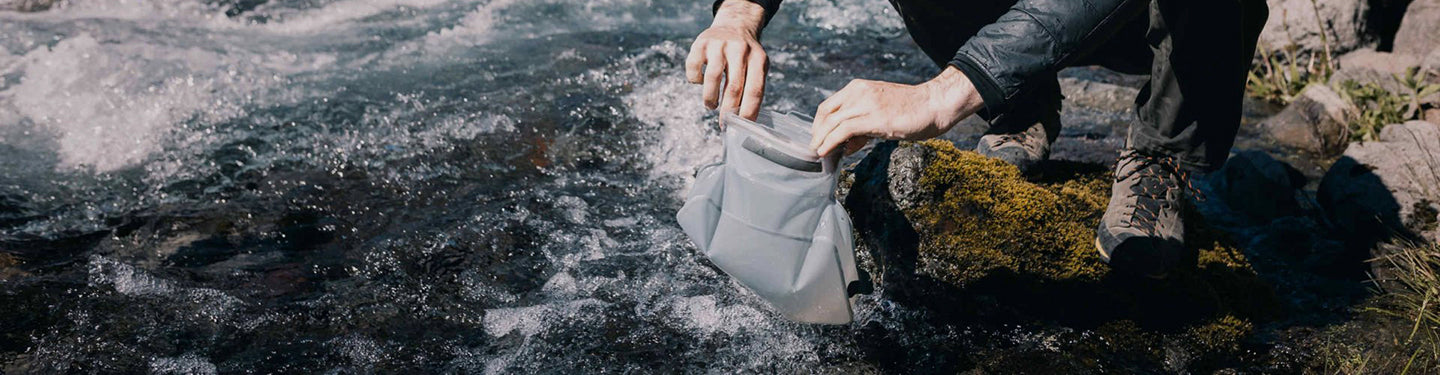 Personne en train de remplir son sac à eau dans la rivière