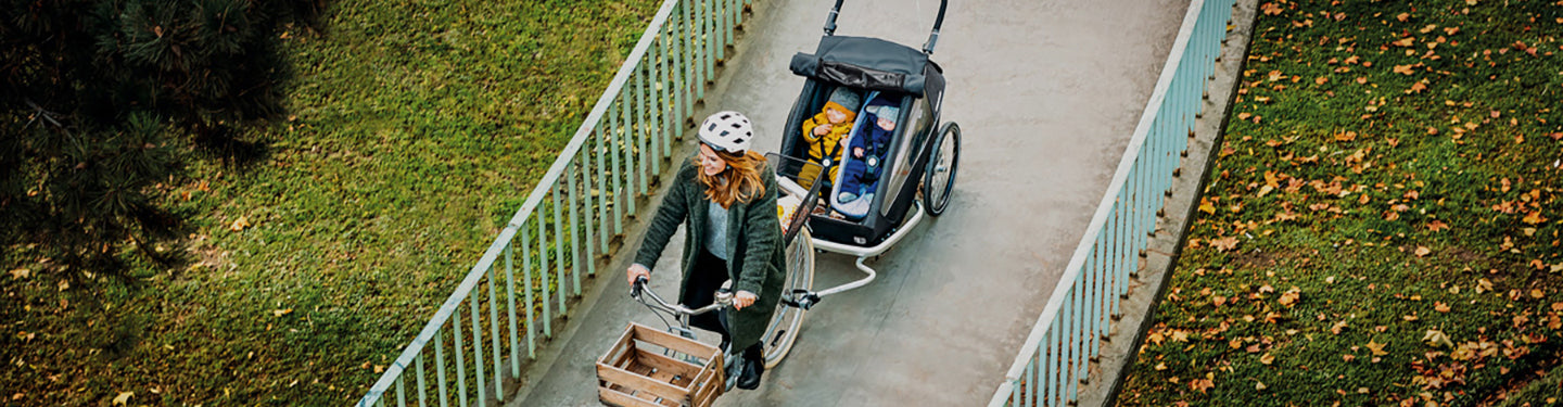 Femme promenant à vélo avec une remorque et des enfants
