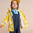 Un enfant porte la salopette imperméable Lammiko Reima avec une veste colorée et une casquette.