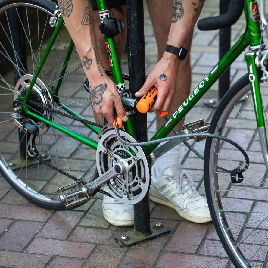 Antivol U combiné Evolution Mini-7 avec câble flex Kryptonite en usage pour sécuriser un vélo vert