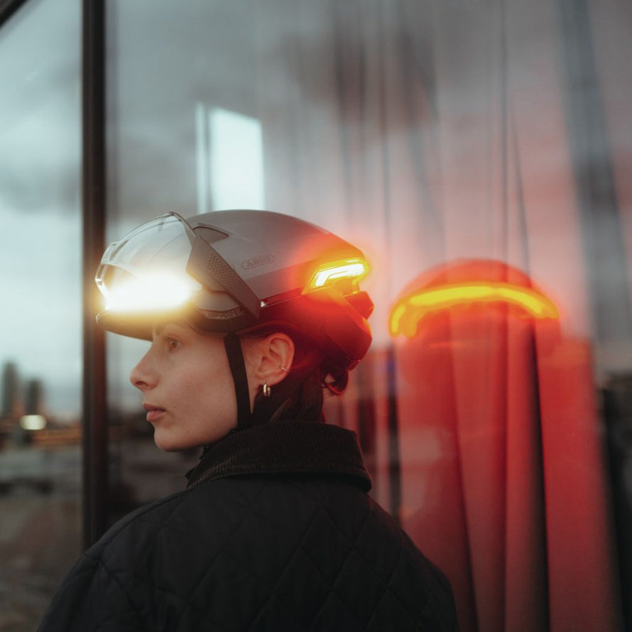 Cycliste urbain portant le casque Abus Hyp-E Ace avec visière transparente et feu arrière intégré idéal pour vélotaf et e-bike