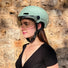 casque velo connecté cosmo fusion vert avec visière intégrée porté par une femme en extérieur