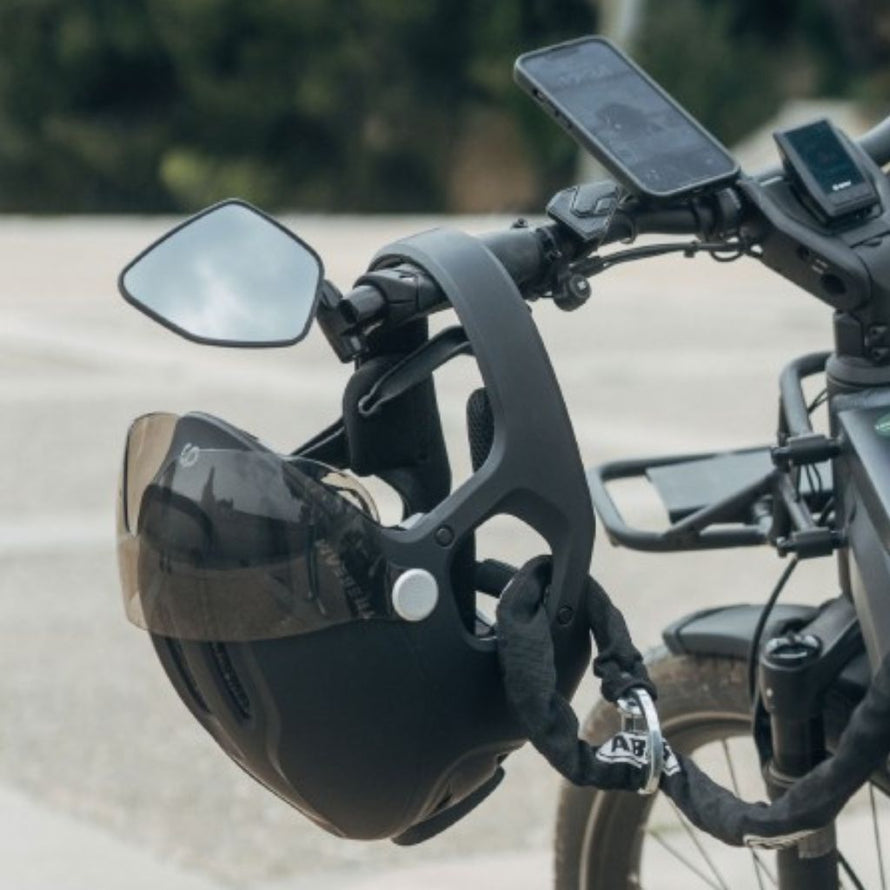 Casque de vélo électrique Virgo Integral noir avec mentonnière et visière, attaché au guidon d’un vélo urbain à assistance électrique.
