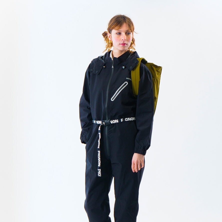Personne portant la combinaison imperméable vélo ENTEGA Pignon Clothing unisexe avec sac à dos vert olive