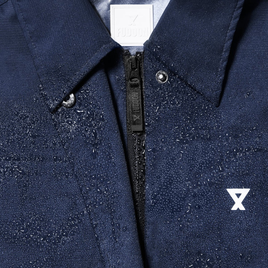 Détail du trench-coat imperméable unisexe Fudoon bleu avec gouttes d'eau sur tissu et fermeture éclair