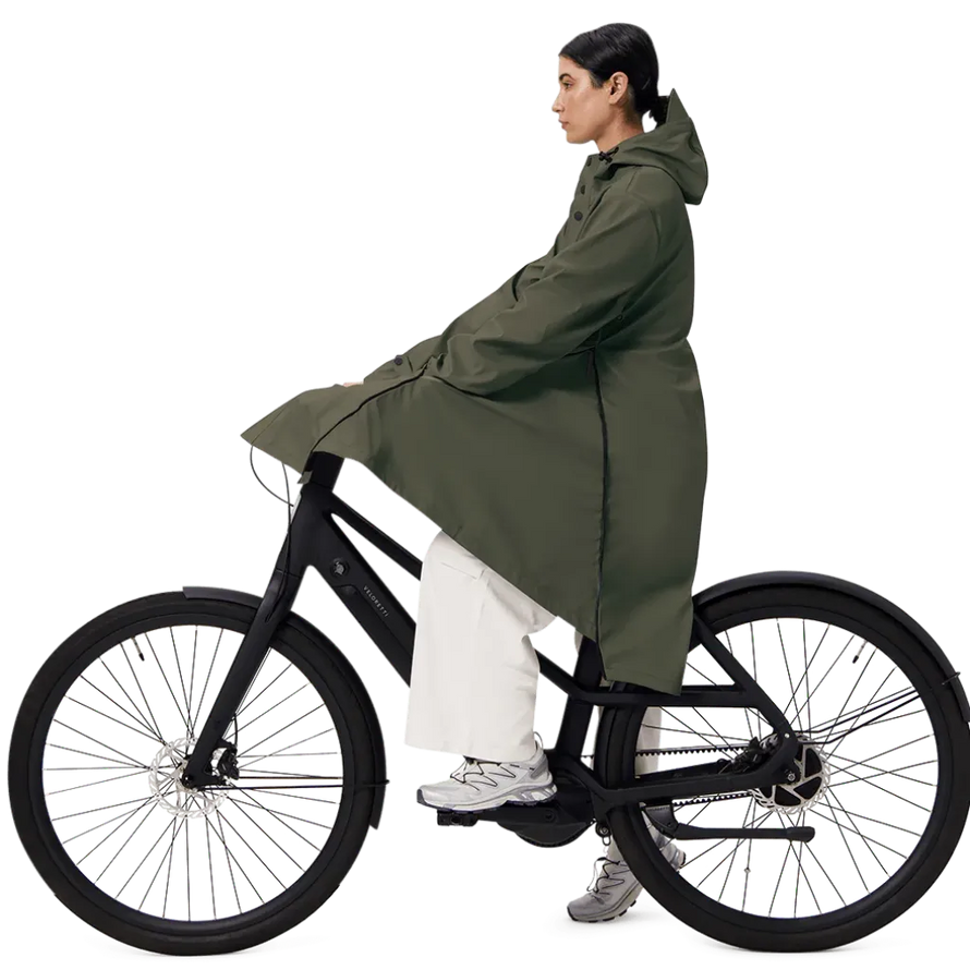 Une femme à vélo porte une parka Maium army green. 