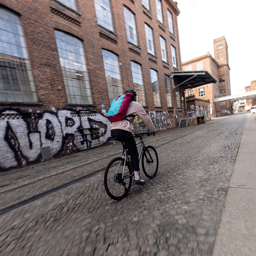 Cycliste urbain avec sac a dos velo etanche Ortlieb Velocity Lite 23L bleu et rose pour trajets quotidiens