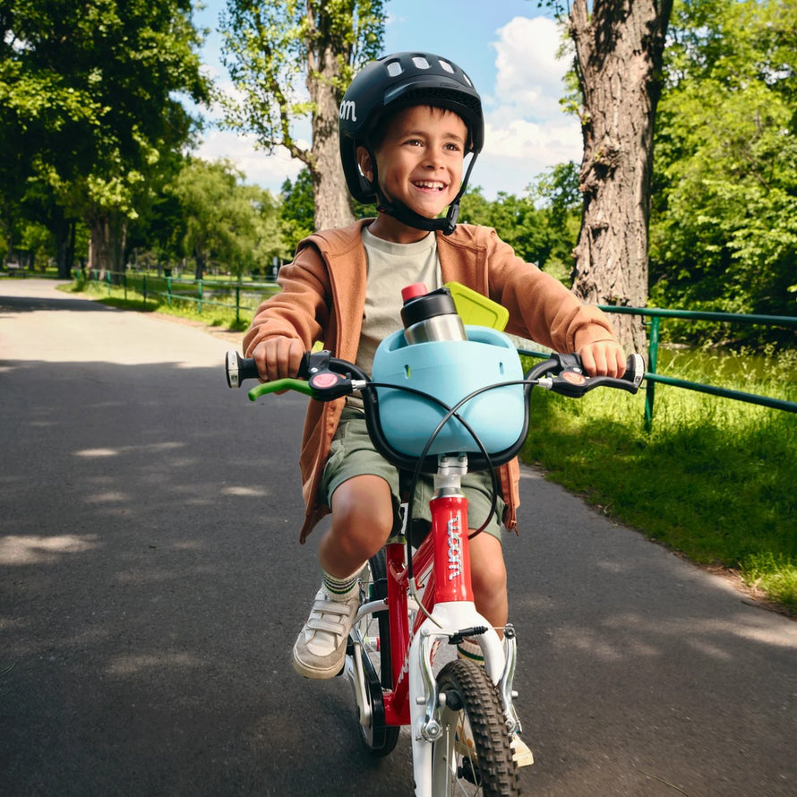 Panier vélo enfant woom pop bleu fixé sur guidon avec gourde et boîte à goûter