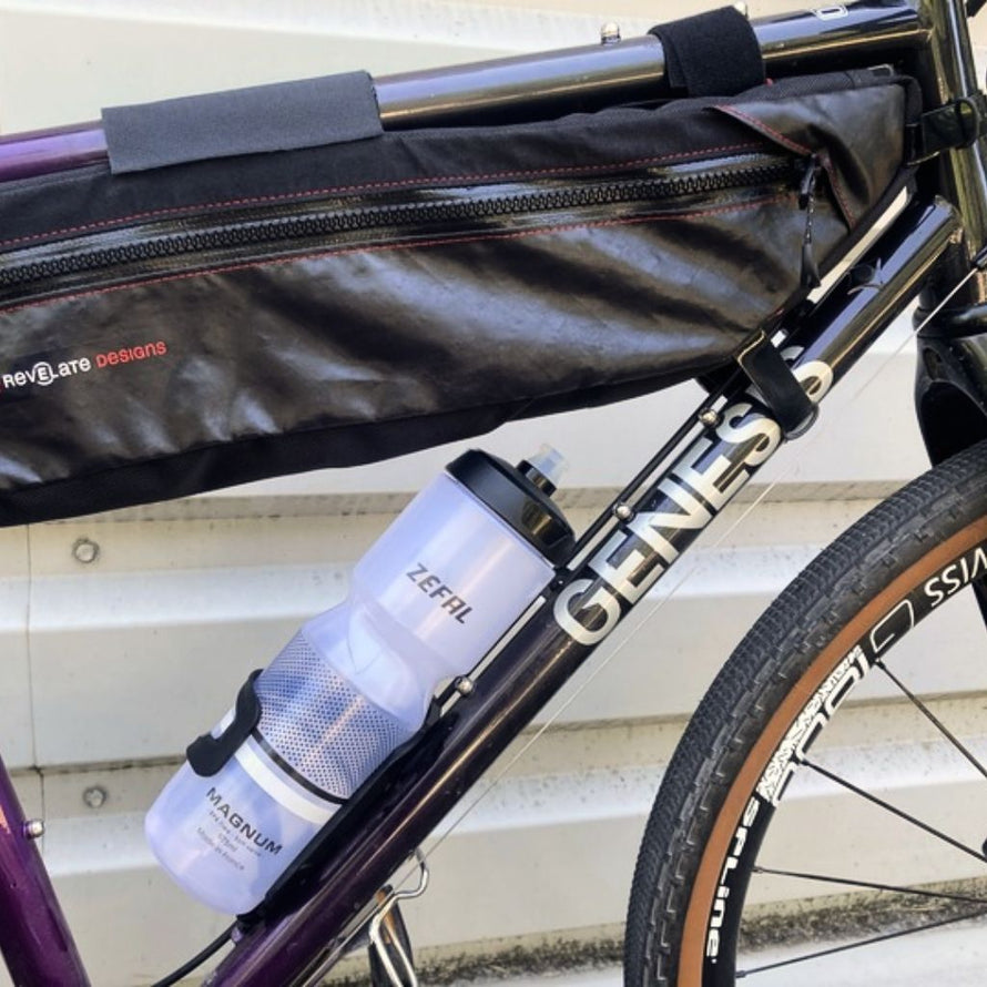 Ce porte-bidon à entrée latérale permet d'emporter un grand bidon d'eau sur un vélo équipé d'une sacoche de cadre sans gêne.