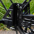Détail de la visserie et de la platine métallique permettant l’installation des roues stabilisatrices sur la roue arrière d’un vélo adulte.