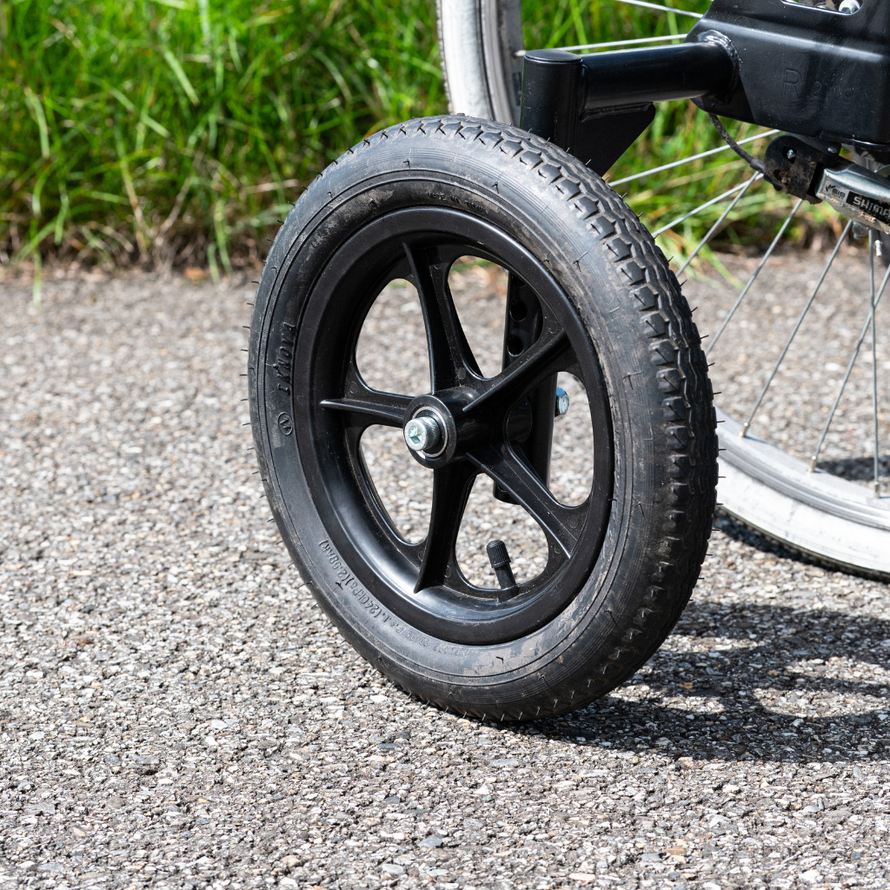Gros plan sur une roue stabilisatrice pour vélo adulte avec jante noire et pneu plein monté sur un axe métallique.