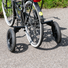 Vue arrière d’un vélo équipé de deux grandes roues stabilisatrices noires, apportant un appui supplémentaire pour l’équilibre.