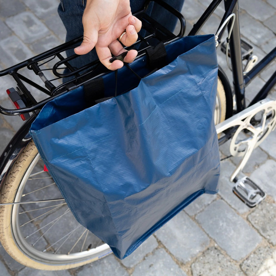 Sac cabas bleu Cobags Bikezac 2.0 20L fixé sur porte-bagages arrière vélo, léger et résistant
