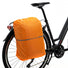 Sacoche convertible en sac à dos Nevada Backpack Newlooxs recouverte de sa housse de pluie et accrochée sur le porte-bagages. 