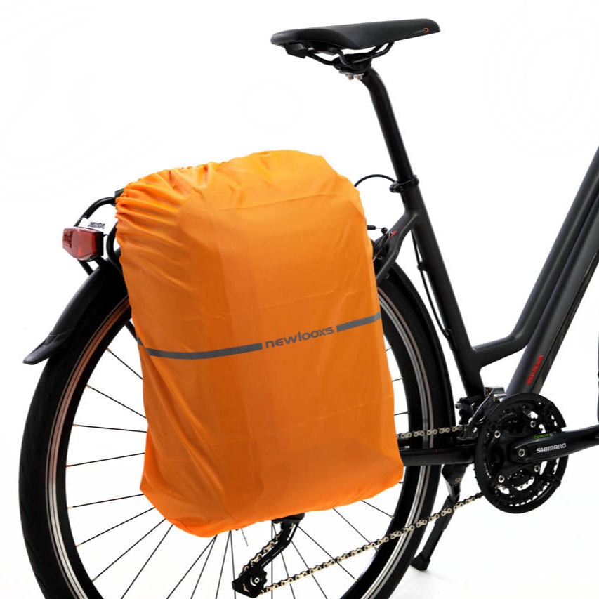 Sacoche convertible en sac à dos Nevada Backpack Newlooxs recouverte de sa housse de pluie et accrochée sur le porte-bagages. 