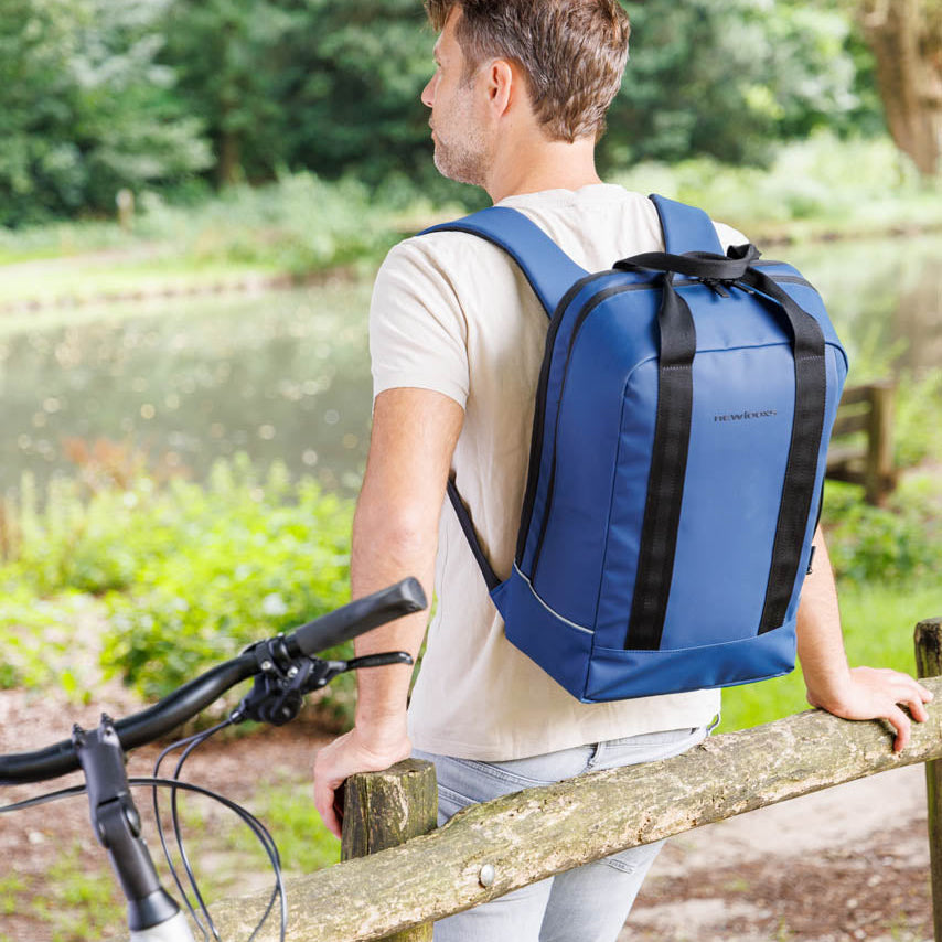 Un homme est debout à côté de son vélo, il porte un sac à dos  convertible en sacoche vélo Nevada Backpack Newlooxs 