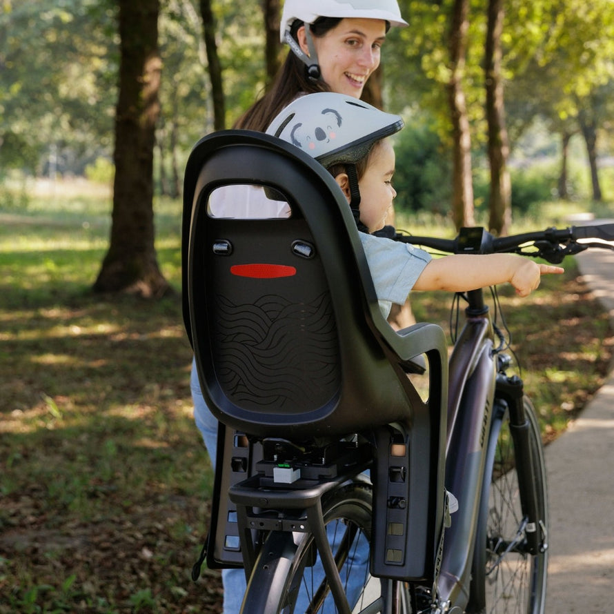 Siège vélo enfant Polisport Groovy MIK-HD noir fixé à vélo avec enfant équipé d'un casque, sécurité et confort assurés
