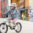 Petite fille souriante roulant vers l’école sur son vélo PUKY LS-PRO 14 vert avec casque rose