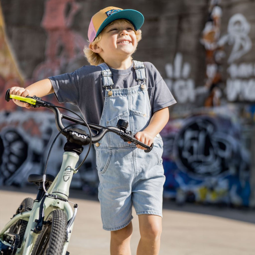 Garçon souriant poussant son vélo PUKY LS-PRO 16 vert, cadre aluminium léger et maniable dès 4 ans
