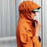 Gros plan sur une femme portant le poncho cuivre Imbris Weathergoods Sweden, capuche réglable pour plus de confort.