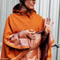 Gros plan d’une femme avec le poncho cuivre Imbris Weathergoods Sweden, tenant la sangle de maintien pour protéger ses mains.