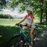 Enfant souriant sur velo woom explore 4 20 pouces vert en balade en plein air pour 6 a 8 ans
